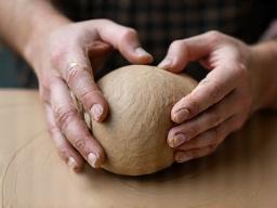 Hands wedging a large piece of clay