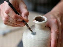 Artisan applying glaze to a ceramic vase